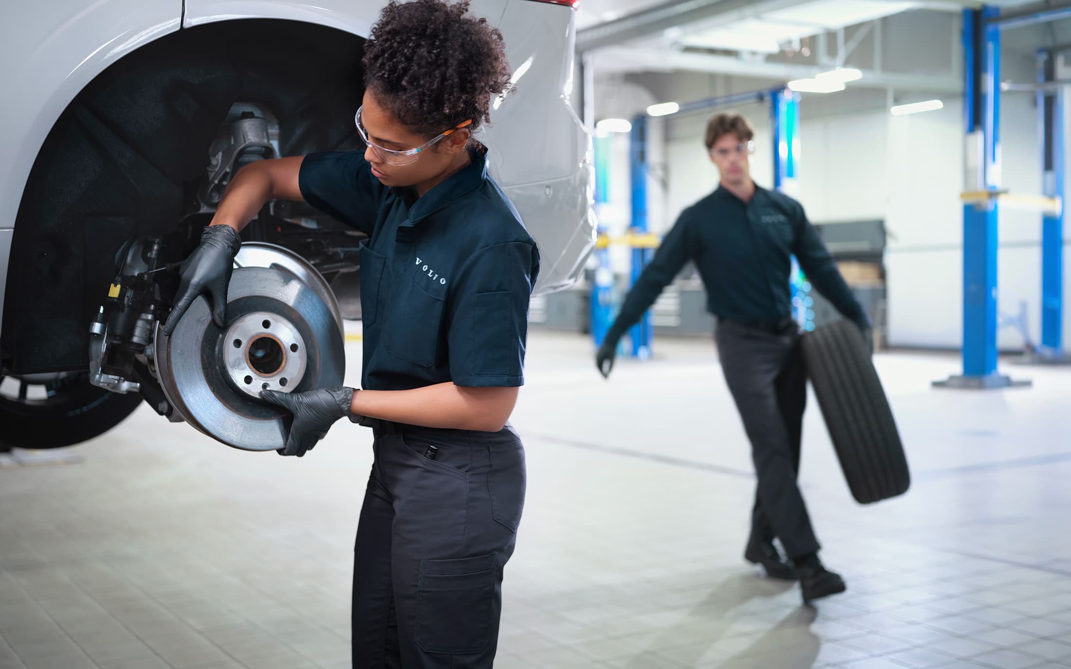 Two automotive technicians inspecting vehicles in a bright service workshop